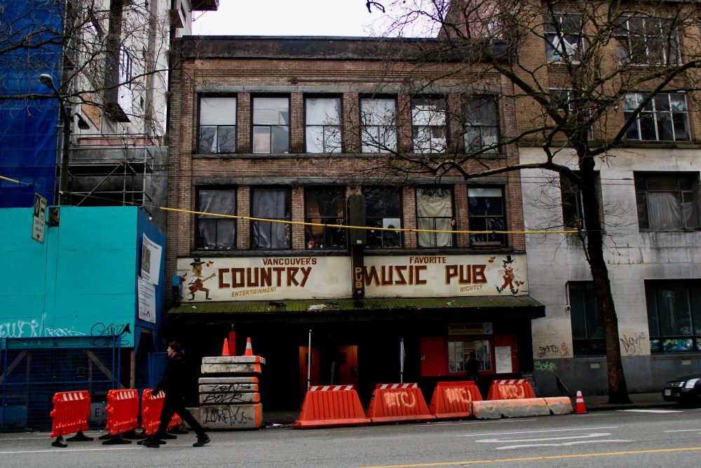 A three-story brick building with a sign that says Country Music Pub.